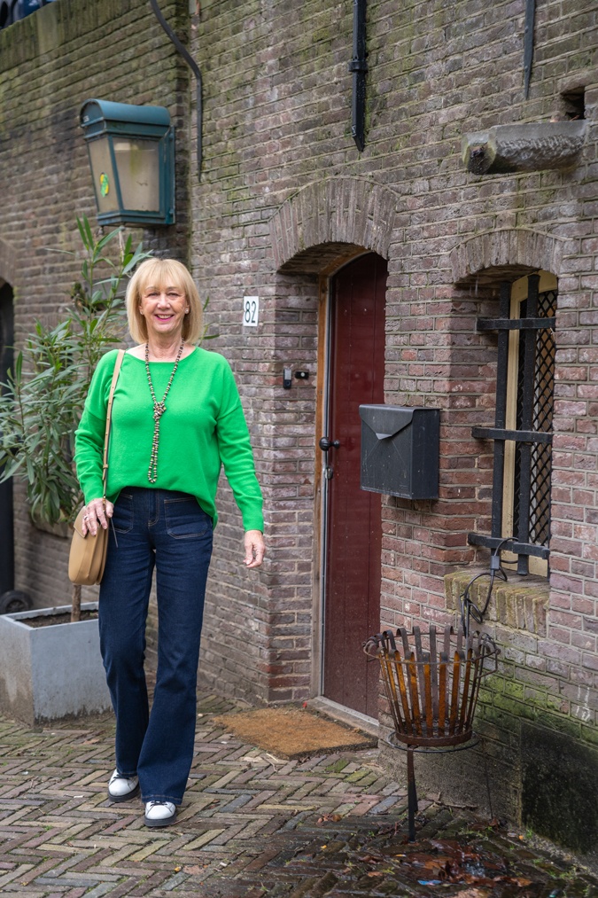 green jumper with flared jeans and trainers